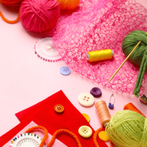 a pink table with buttons, thread, wool, knitting needles, pins and felt